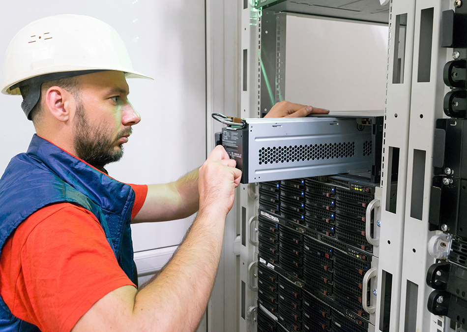 Field Service Engineer installs a new battery pack into an uninterruptible power supply (UPS).