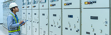 Worker checking status of switchgear electrical energy distribution in substation room.